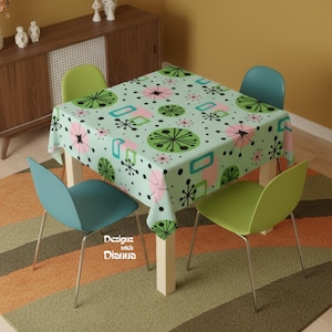 May include: A square tablecloth with a retro design featuring pink, green, and black shapes on a light green background. Four modern chairs in blue and green surround a wooden table. The rug has orange, brown, and green stripes. Text reads "Designs with Dianna."
