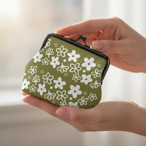 May include: An olive green coin purse with a white floral pattern. The purse has a black clasp and a kiss-lock closure. The floral design includes various flower shapes and sizes.