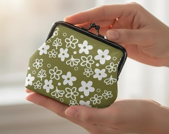 May include: A small olive green coin purse featuring a repeating white floral pattern and a black metal kiss-lock clasp. The pouch has a structured frame and a smooth surface, decorated with various sizes of five-petaled flowers and small circles.