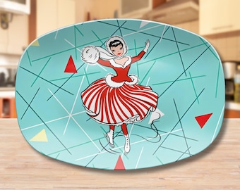 May include: A turquoise oval serving platter with a white and red striped design featuring a woman ice skating. The background has a geometric pattern of white and turquoise lines.