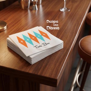 May include: A stack of white cocktail napkins with a retro design of orange and turquoise diamonds, each with a starburst center. The text "Tom's Bar" is printed below the design. The words "Designs with Dianna" are printed on the right side.
