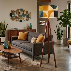 May include: A mid-century modern living room with a gray sofa, wooden coffee table, and a geometric patterned floor lamp. The lamp has a wooden tripod base and a shade with a geometric pattern in shades of yellow, teal, and black. Decorative pillows in shades of yellow and patterned pillows are on the sofa.