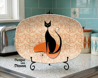 May include: An oval decorative plate with a black cat silhouette on an orange shape, set against a cream background with a retro pattern. The plate is displayed on a black metal stand. The text "Designs with Dianna" is visible.
