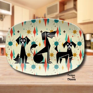 May include: An oval serving platter with a retro design featuring three stylized black dogs against a cream background. The background has a repeating pattern of diamonds and starbursts in teal, red, and yellow. The platter has the text "Designs with Dianna".