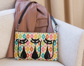 May include: A colorful crossbody bag featuring a retro geometric pattern with three black cat silhouettes. The bag has a black strap and a zipper closure. The background is a mix of diamonds in various colors.