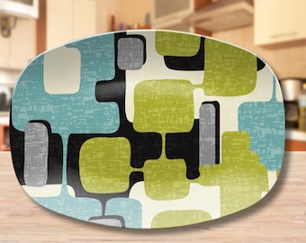 May include: An oval serving platter featuring a repeating abstract pattern of rounded rectangular shapes in shades of lime green, light blue, and gray, all interconnected by thick black lines against a cream-colored background.