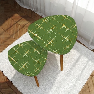 May include: Two green, mid-century modern style side tables with a geometric pattern in white and gold. The tables have a rounded triangular shape and are supported by three wooden legs. They are placed on a white shag rug.
