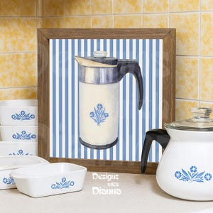May include: A framed watercolor print of a vintage coffee pot with a blue floral design, set against a blue and white striped background. White ceramic dishes with blue floral patterns are in the foreground. The text "Designs with Dianna" is visible.