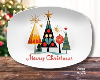 May include: White oval serving platter with a retro Christmas tree design. The trees are in various colors and shapes, with gold star and burst accents. The words "Merry Christmas" are written in red.