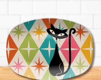 May include: An oval-shaped serving platter featuring a black cat illustration with almond-shaped eyes and a long tail. The background displays a repeating pattern of colorful diamonds in shades of orange, lime green, teal, pink, and yellow, each accented with a white starburst design.