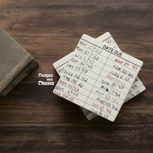 May include: Two square white ceramic coasters featuring a printed library book date due card design. The black and red text includes columns for dates ranging from 1962 to 1965. The text Designs with Dianna is printed on the left side of the coasters.