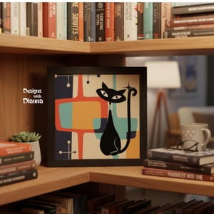May include: A square framed wall art piece featuring a stylized black cat illustration against a background of overlapping geometric shapes in teal, orange, and dark blue. The text Designs with Dianna is printed in white on the left side.