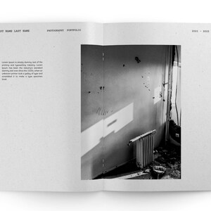 May include: Black and white photograph of a room with a radiator and a door. The room is empty and the walls are peeling. The light from the window casts shadows on the wall.