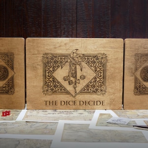 May include: Three wooden boxes with intricate designs and the text "The Dice Decide" on the center box. The boxes are closed and sitting on a table with a map and other game pieces.