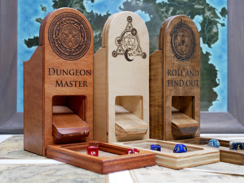 Puede incluir: Tres torres de dados de madera con dise&ntilde;os y texto grabados. Las torres est&aacute;n hechas de diferentes tonos de madera y tienen una ranura para tirar los dados. Las torres est&aacute;n etiquetadas como "Dungeon Master", "Roll and Find Out" y una tercera torre con una luna creciente y un s&iacute;mbolo de dado D20.