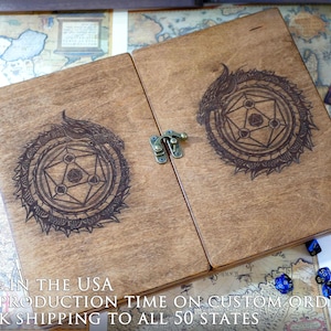 May include: A wooden box with a hinged lid, featuring a laser-engraved design of a dragon curled around a geometric symbol. The box has a brass latch and is made in the USA. "MADE IN THE USA FAST PRODUCTION TIME ON CUSTOM ORDERS QUICK SHIPPING TO ALL 50 STATES" is printed on the bottom of the box.