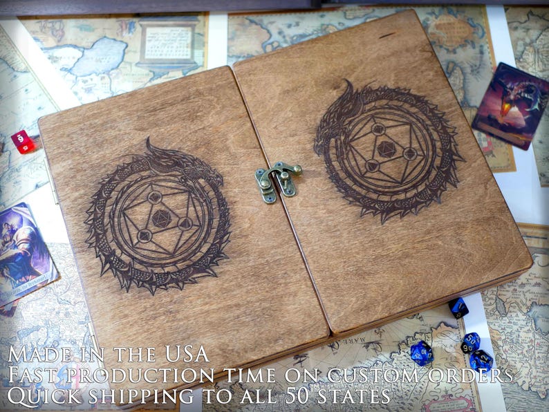 May include: A wooden box with a hinged lid, featuring a laser-engraved design of a dragon curled around a geometric symbol. The box has a brass latch and is made in the USA. "MADE IN THE USA FAST PRODUCTION TIME ON CUSTOM ORDERS QUICK SHIPPING TO ALL 50 STATES" is printed on the bottom of the box.