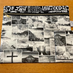 May include: Black and white zippered pouch and matching wallet featuring a collage of religious imagery, including crosses, landscapes, and inspirational text. The pouch has a gold zipper and the text "Lord of Kings" and "Lamb of God".