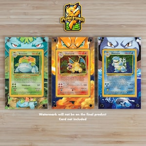 Peut inclure: Trois présentoirs pour cartes Pokémon avec des cartes Venusaur, Charizard et Blastoise. Les cartes sont dans des étuis de protection transparents. Un logo Pokeminh jaune et vert est en haut. Le texte "Watermark will not be on the final product Card not included" est en bas.