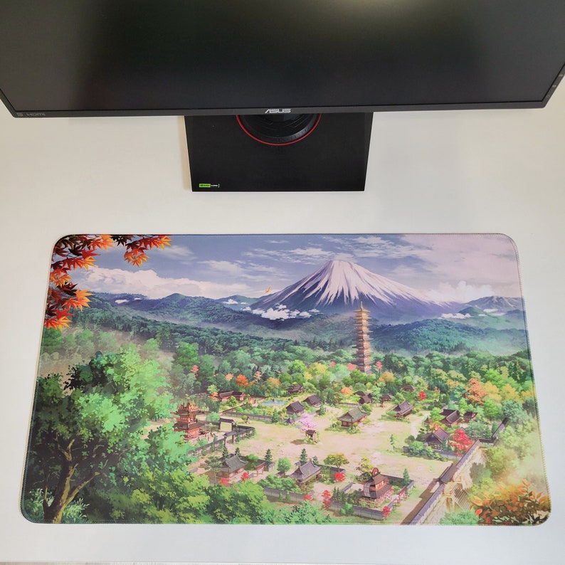 May include: A colorful anime-style illustration of a Japanese mountain village with a pagoda and Mount Fuji in the background. The illustration is printed on a rectangular mousepad.