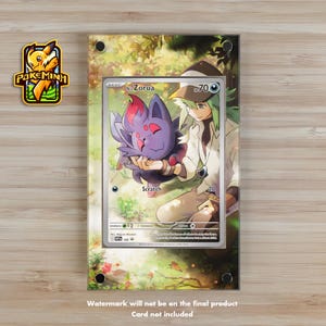 Puede incluir: Una pantalla acrílica transparente con una carta coleccionable de Pokémon que presenta una criatura morada y roja. La carta está colocada sobre un fondo de una persona y una escena de bosque. La pantalla tiene un logotipo en la esquina superior izquierda y texto en la parte inferior.