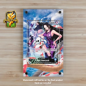 May include: A clear acrylic display featuring a One Piece trading card with Boa Hancock. The card has a purple and white design with a skull and the number 5000. The display is on a light brown surface.