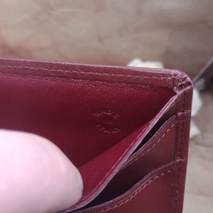 May include: The inside of a burgundy leather wallet with the text "Cartier Paris" embossed in gold.
