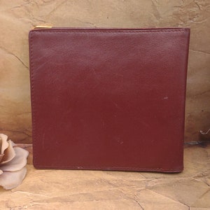 May include: A burgundy leather wallet with a gold zipper.