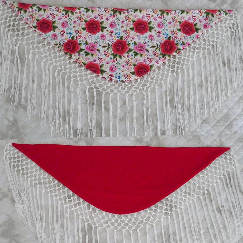 May include: Two triangular shawls. The top shawl has a floral pattern with red and pink roses on a white background. The bottom shawl is solid red. Both shawls have white crocheted edges with long fringe.