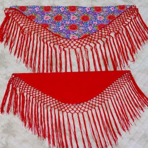 May include: Two triangular shawls. One has a red fringe and a floral pattern on a purple background. The other is solid red with a red fringe. The shawls are likely for dance or costume.