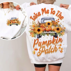 May include: White sweatshirt with a graphic of a vintage truck filled with pumpkins and sunflowers. The text "Take Me To The Pumpkin Patch" is printed on the sweatshirt.