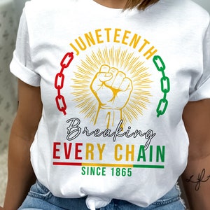 Peut inclure: T-shirt blanc avec un motif graphique repr&eacute;sentant un poing lev&eacute;, des cha&icirc;nes et le texte "Juneteenth Breaking Every Chain Since 1865".
