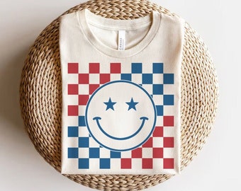 May include: A white t-shirt with a red and blue checkered pattern and a blue smiley face with two stars above the eyes.