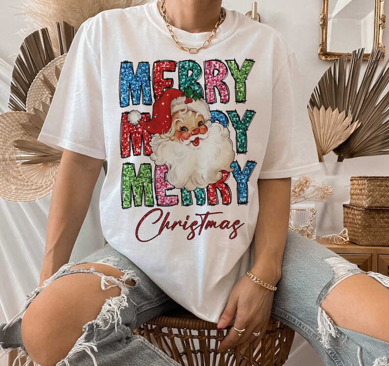 Op de afbeelding: Wit T-shirt met een kleurrijke, glinsterende "Merry Christmas"-afbeelding met een vintage illustratie van de kerstman.