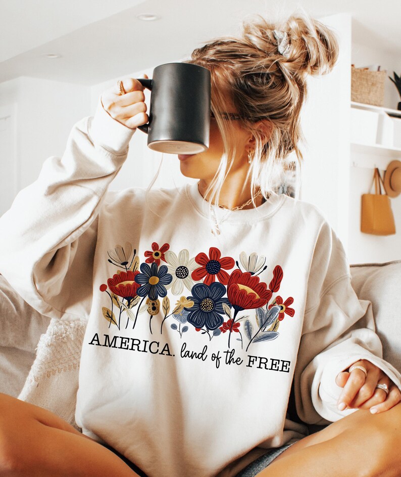 May include: A white sweatshirt with a floral design and the text "AMERICA. land of the FREE".