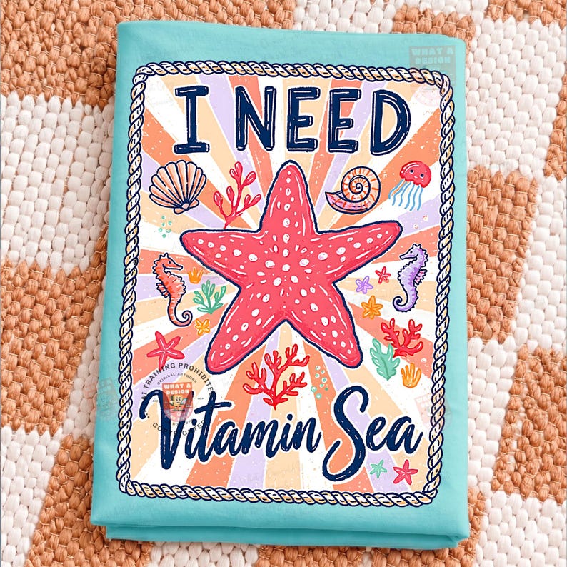 May include: A turquoise beach towel with a colorful graphic. The graphic features a red starfish, seashells, seahorses, and the words "I NEED Vitamin Sea" in a playful font. The design is framed with a rope-like border.