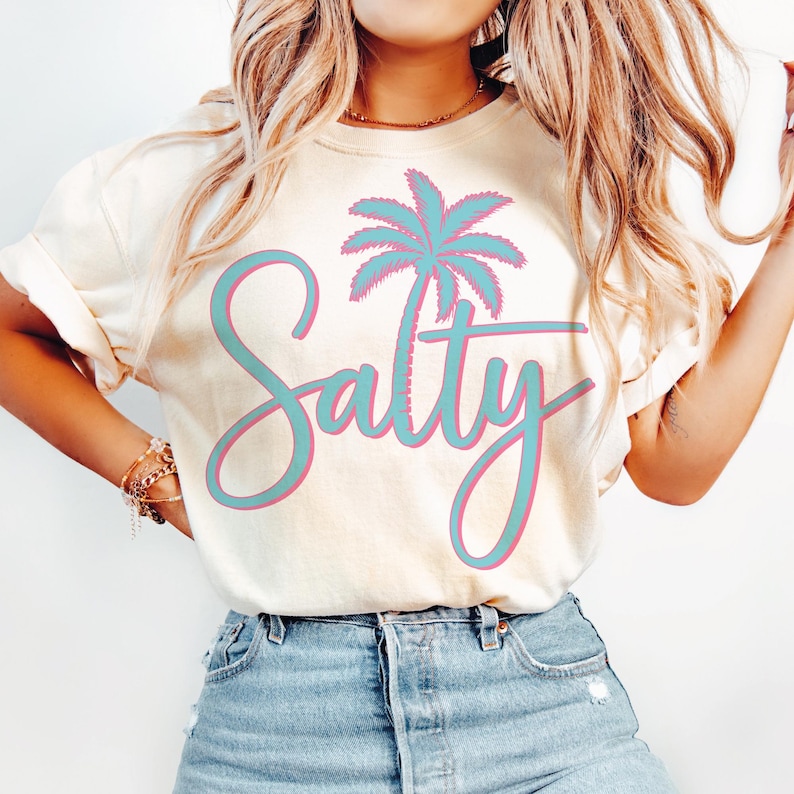 May include: A white t-shirt with a blue palm tree and the word "Salty" in pink and blue lettering.
