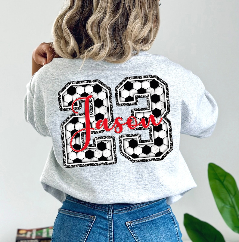 May include: Gray sweatshirt with a large black and white number 23 made of soccer balls. The name "Jason" is written in red cursive inside the number.