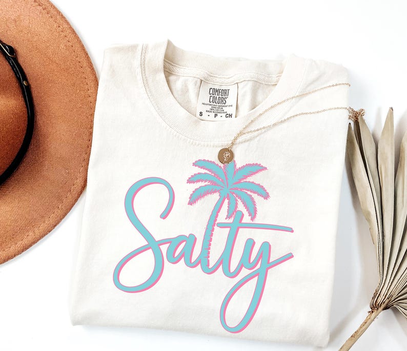 May include: A white t-shirt with a blue and pink palm tree graphic and the word "Salty" in a blue and pink script font.