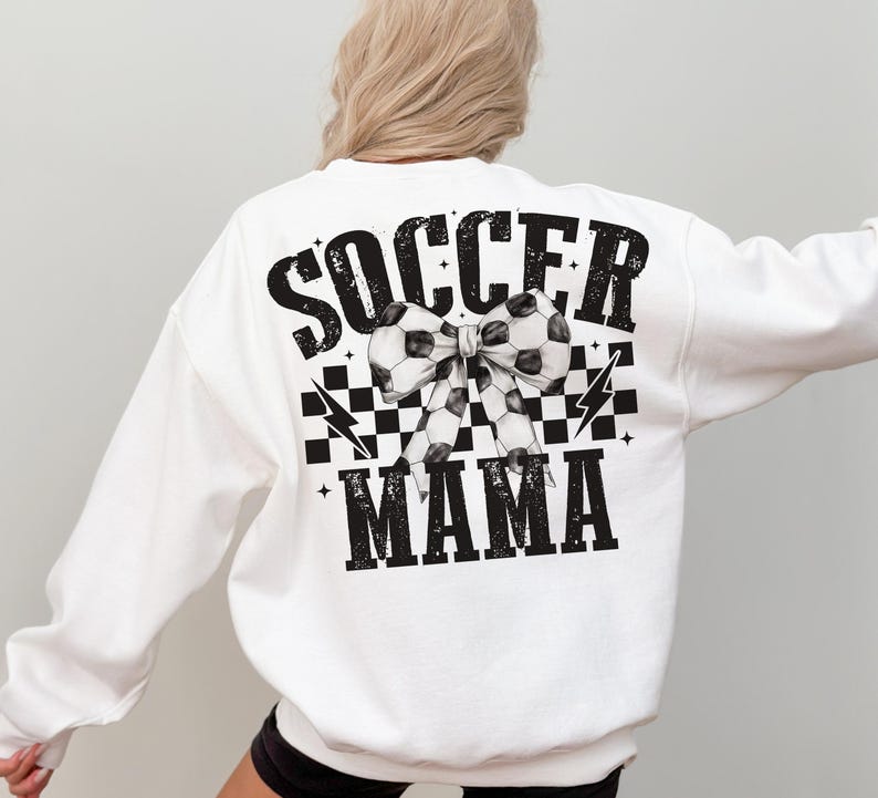 Puede incluir: Sudadera blanca con texto negro que dice "Soccer Mama" con un patr&oacute;n de cuadros blanco y negro y un lazo de bal&oacute;n de f&uacute;tbol blanco y negro.
