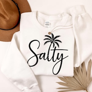 May include: White sweatshirt with a black palm tree and the word "Salty" in a cursive font.