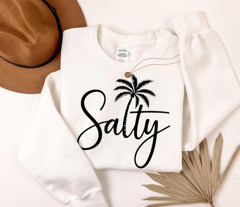 May include: White sweatshirt with a black palm tree and the word "Salty" in a cursive font.