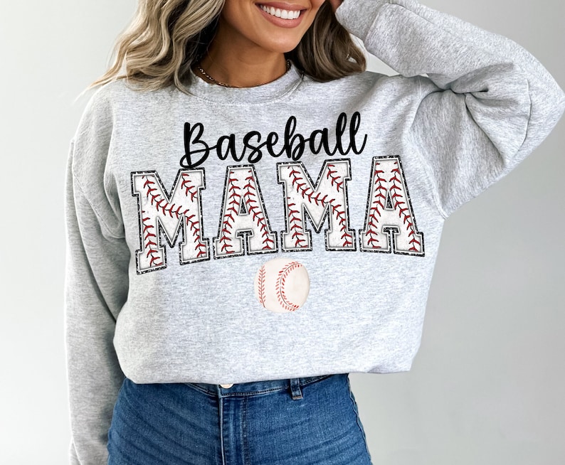 May include: A gray sweatshirt with the text "Baseball Mama" in black lettering. The letters are outlined in red stitching, and a baseball is pictured below the text.