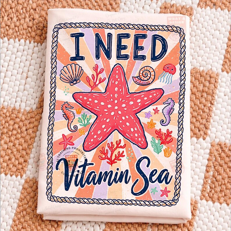 May include: A light pink beach towel with the text "I NEED Vitamin Sea" in navy blue script. The towel features a red starfish, seahorses, seashells, and coral illustrations. The design is framed with a rope border.