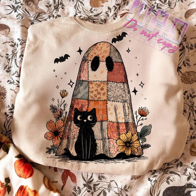 May include: Cream-colored sweatshirt featuring a patchwork ghost design with a black cat, flowers, and bats. The ghost has a patchwork design in shades of orange, brown, and beige. The black cat sits at the bottom of the ghost. Bats and stars are scattered around the ghost.