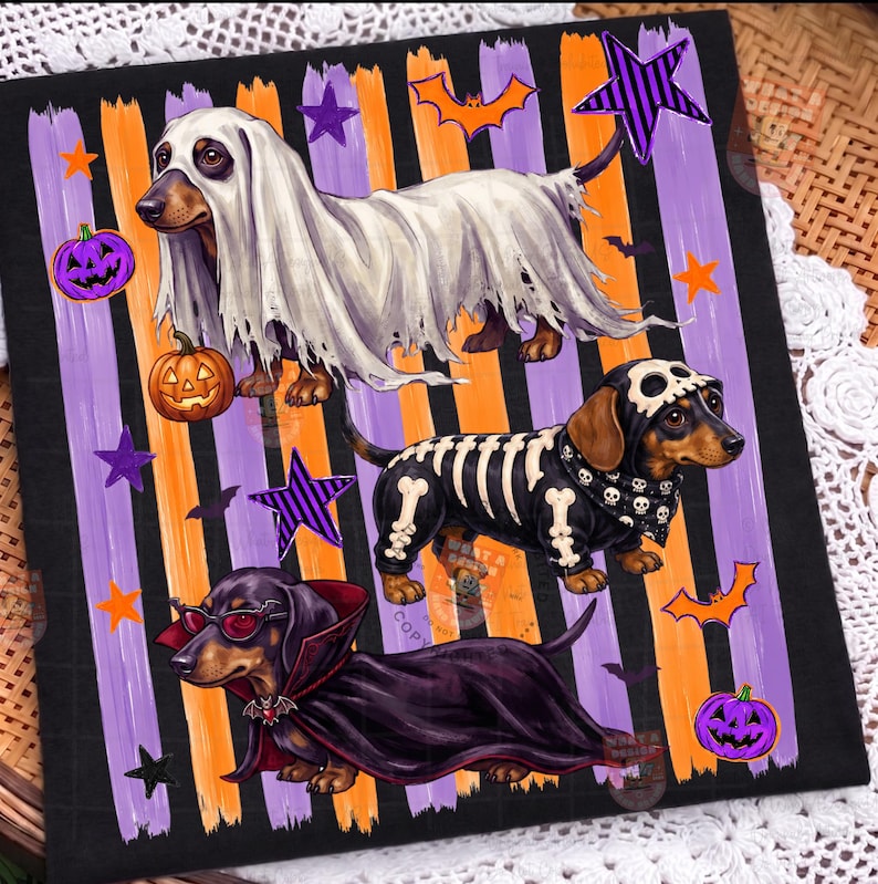 May include: A black fabric square featuring three dachshunds in Halloween costumes: one as a ghost, one as a skeleton, and one as a vampire. The background has vertical orange and purple brushstrokes, orange pumpkins, purple stars, and bats.