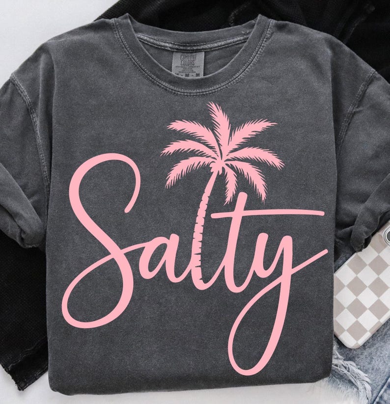 May include: A dark gray t-shirt with a pink palm tree and the word "Salty" in pink script.