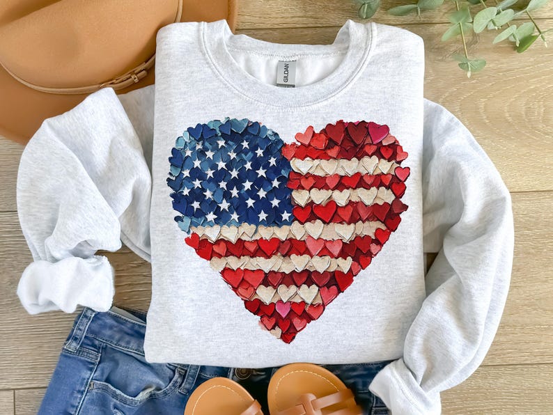 May include: A gray sweatshirt with a heart-shaped design made of small red, white, and blue hearts. The design resembles the American flag.