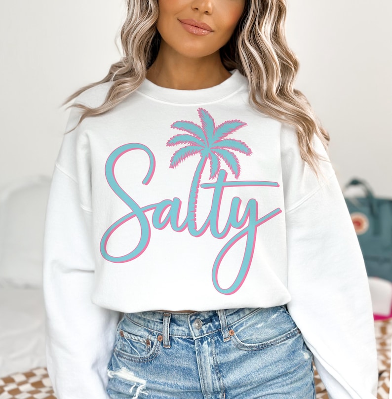 May include: White sweatshirt with a blue and pink palm tree graphic and the text "Salty" in a blue and pink script font.