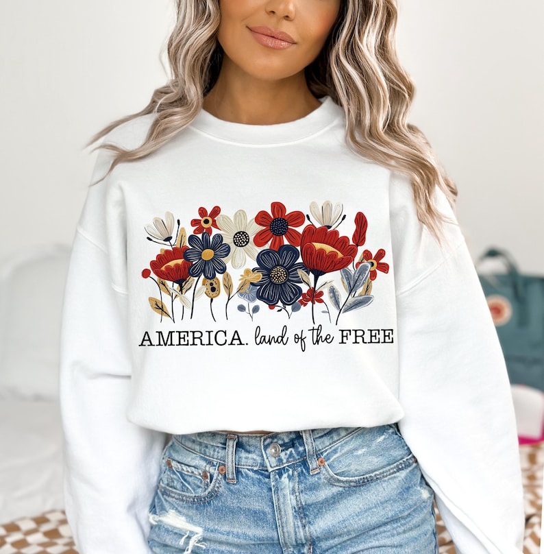 May include: White sweatshirt with a red, white, and blue floral design and the text "AMERICA. land of the FREE".